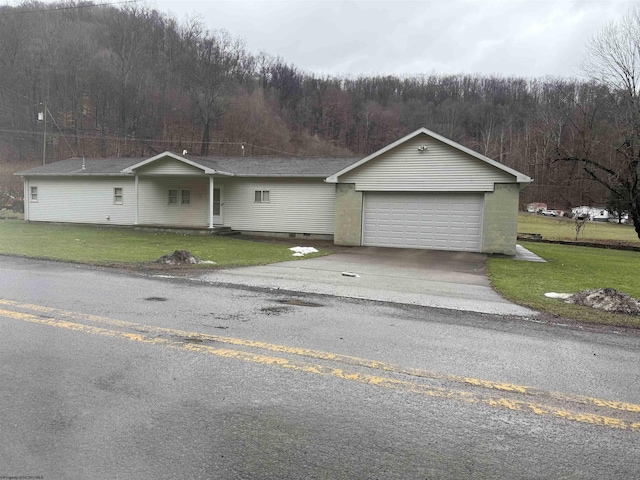 ranch-style home featuring driveway, a forest view, an attached garage, crawl space, and a front lawn