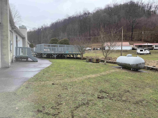 view of yard featuring a forest view and a wooden deck