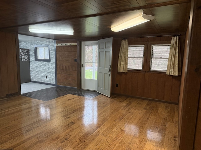 foyer featuring wooden ceiling, brick wall, wooden walls, and wood finished floors