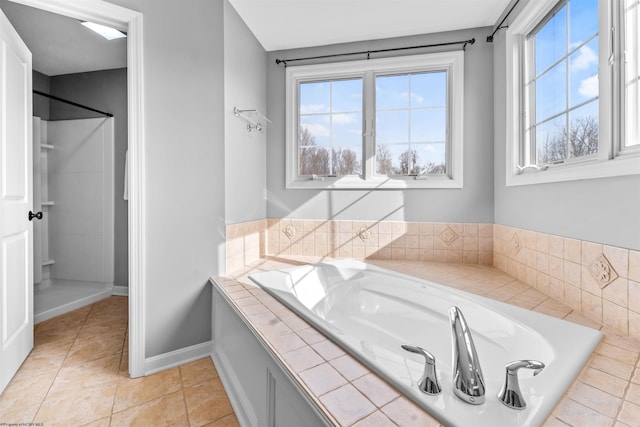 bathroom with a relaxing tiled tub, tile patterned floors, and a healthy amount of sunlight