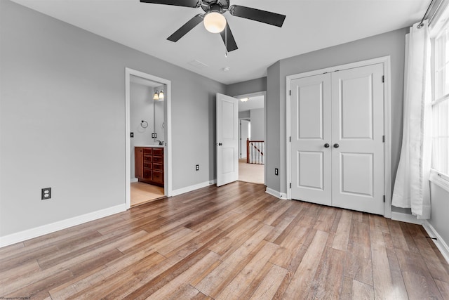 unfurnished bedroom with ensuite bath, a closet, ceiling fan, and light wood-type flooring