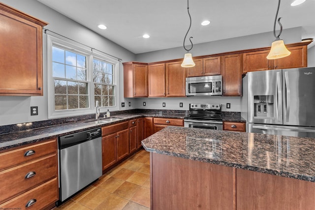 kitchen with stainless steel appliances, sink, hanging light fixtures, and dark stone counters