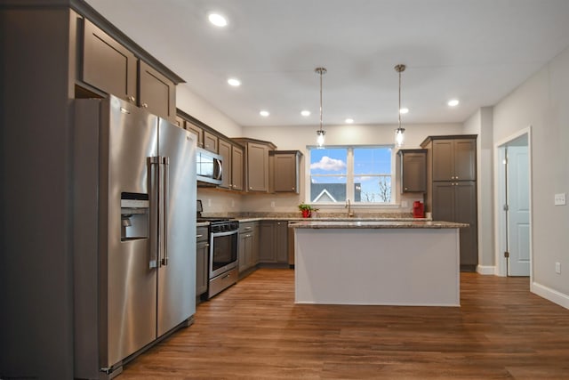 kitchen with a kitchen island, sink, dark hardwood / wood-style flooring, hanging light fixtures, and stainless steel appliances