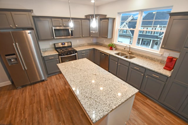 kitchen featuring sink, light stone counters, hanging light fixtures, a kitchen island, and stainless steel appliances