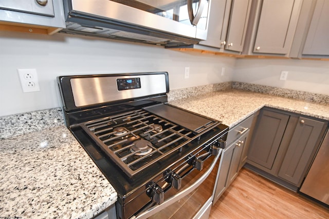 kitchen with light hardwood / wood-style flooring, light stone countertops, and appliances with stainless steel finishes