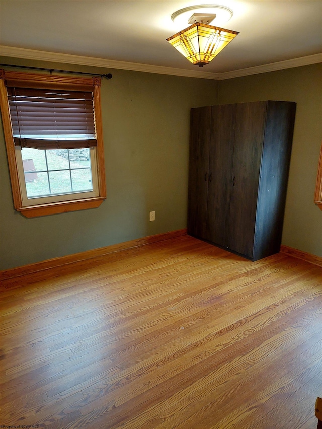 unfurnished bedroom with crown molding and light wood-type flooring