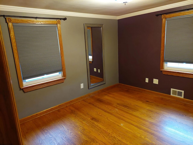 spare room featuring wood-type flooring and crown molding