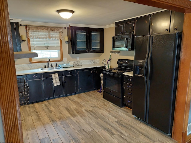 kitchen with ornamental molding, sink, light wood-type flooring, and black appliances