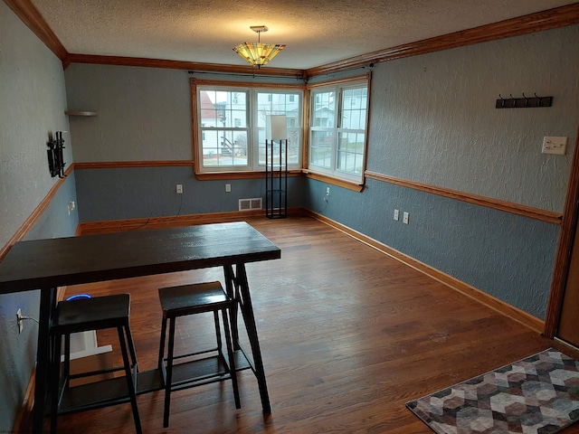 dining area featuring crown molding, dark wood-type flooring, and a textured ceiling