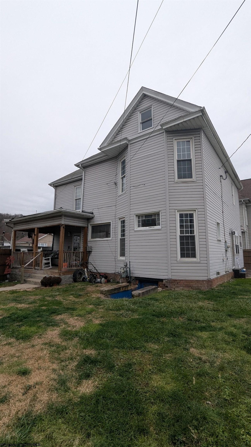 back of house featuring covered porch and a lawn