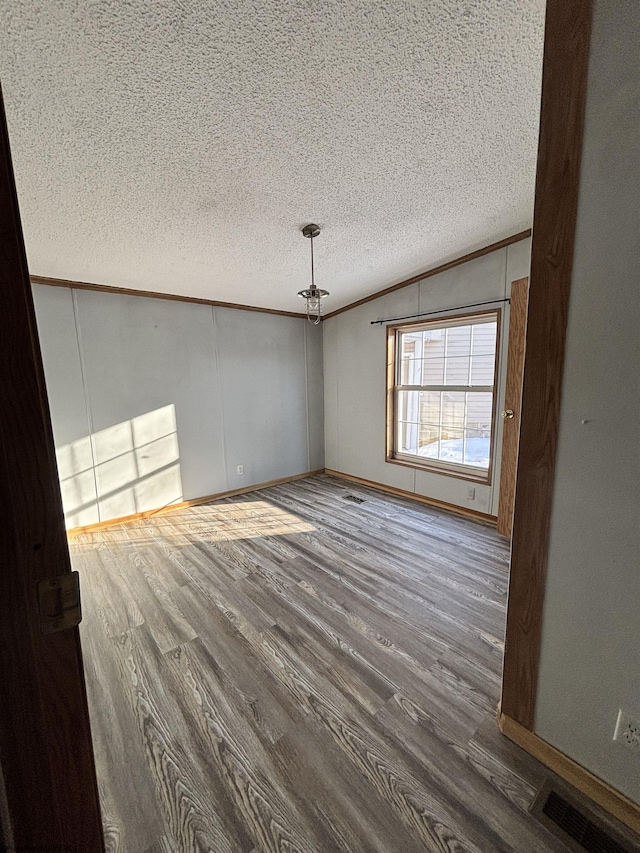 unfurnished room featuring crown molding, lofted ceiling, wood-type flooring, and a textured ceiling