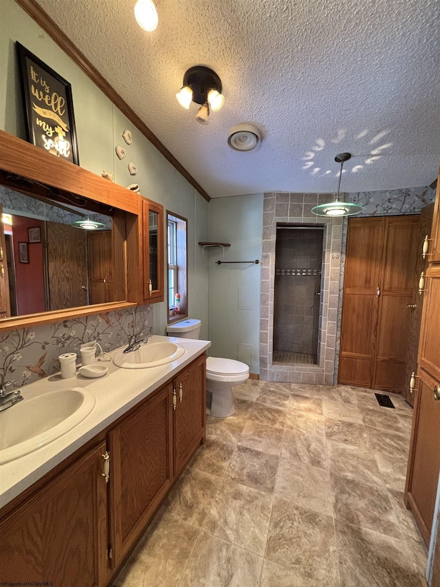 bathroom featuring lofted ceiling, toilet, a textured ceiling, a tile shower, and vanity