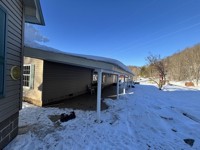 view of snow covered exterior with a carport