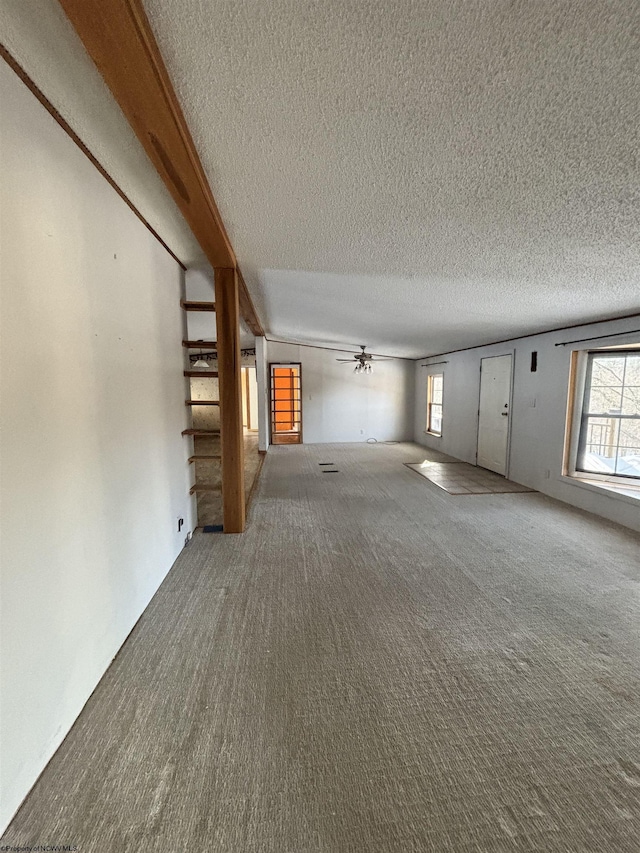 unfurnished living room with plenty of natural light, carpet flooring, and a textured ceiling