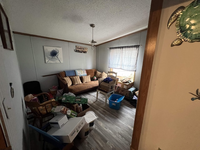 living room featuring wood-type flooring, lofted ceiling, crown molding, and a textured ceiling