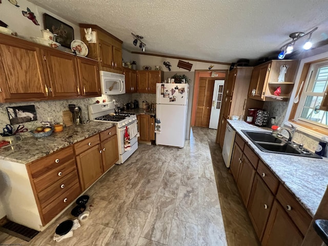 kitchen featuring sink, white appliances, tasteful backsplash, light stone countertops, and a textured ceiling