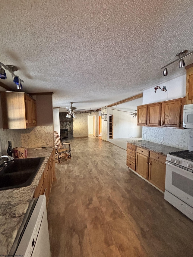 kitchen featuring sink, white appliances, a textured ceiling, ceiling fan, and backsplash