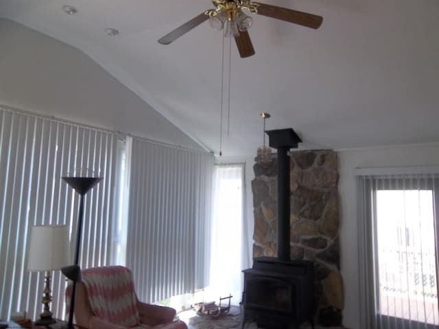 living room with lofted ceiling, a wood stove, and ceiling fan