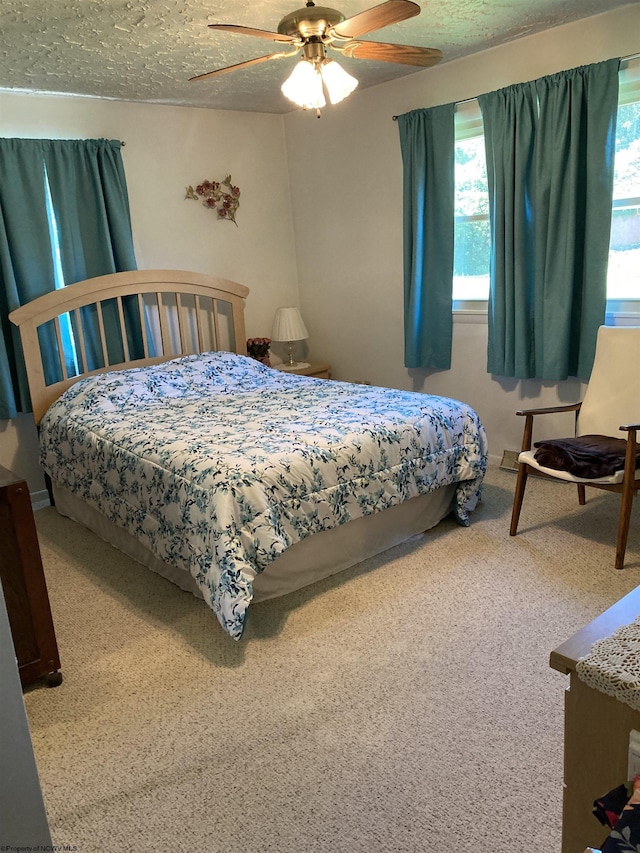 carpeted bedroom with ceiling fan and a textured ceiling