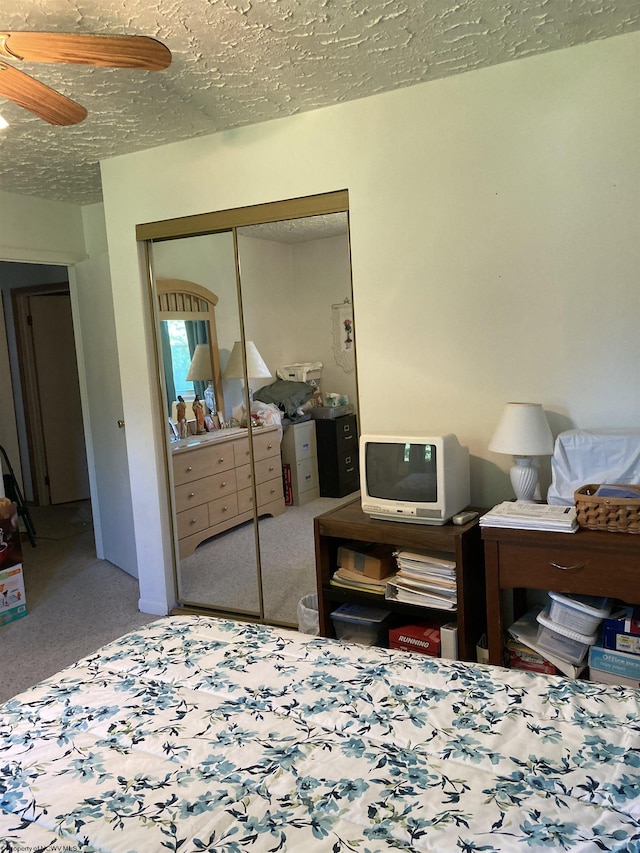 carpeted bedroom featuring ceiling fan, a textured ceiling, and a closet