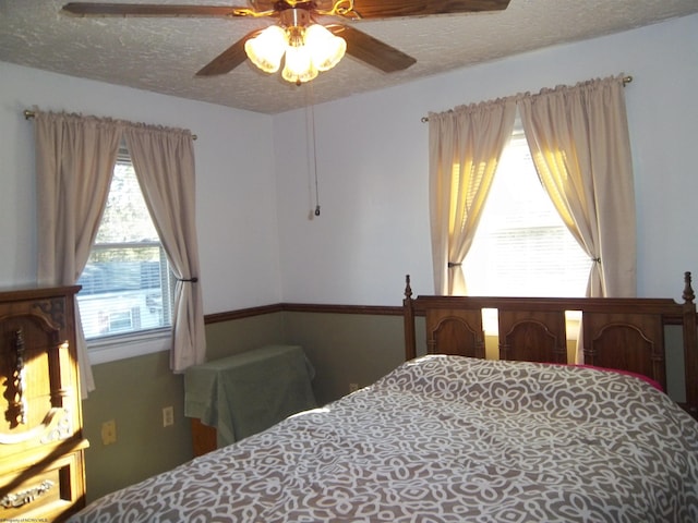 bedroom with ceiling fan and a textured ceiling