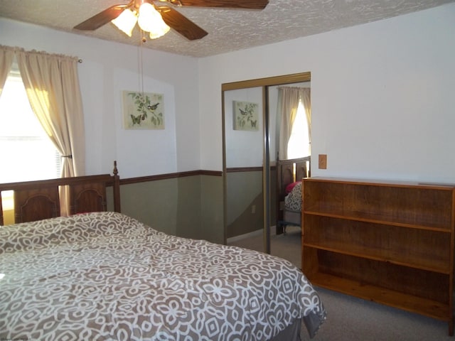 carpeted bedroom with ceiling fan, a closet, and a textured ceiling