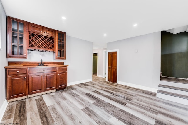 bar with butcher block counters, sink, and light hardwood / wood-style flooring