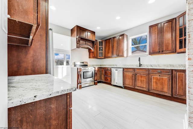 kitchen featuring stainless steel appliances, sink, a healthy amount of sunlight, light stone countertops, and light hardwood / wood-style floors