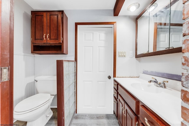 bathroom with vanity, hardwood / wood-style flooring, beam ceiling, and toilet