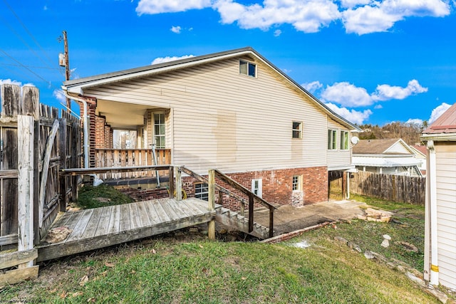 back of house with a deck, a patio area, and a lawn