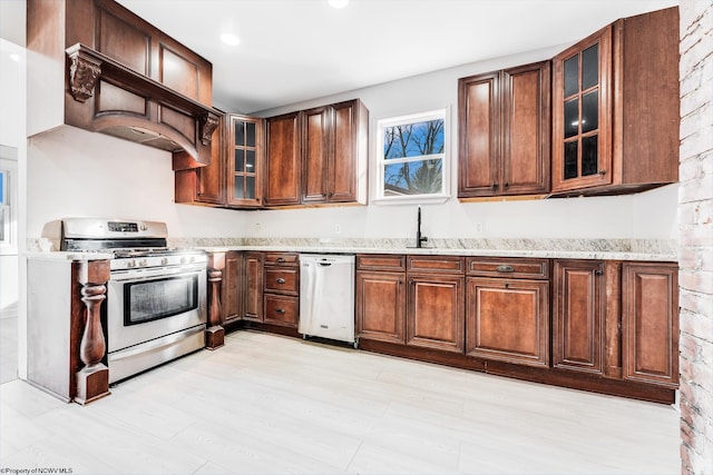 kitchen with appliances with stainless steel finishes, sink, and light stone counters