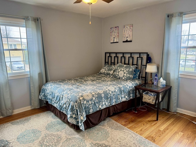 bedroom featuring hardwood / wood-style flooring, ceiling fan, and multiple windows