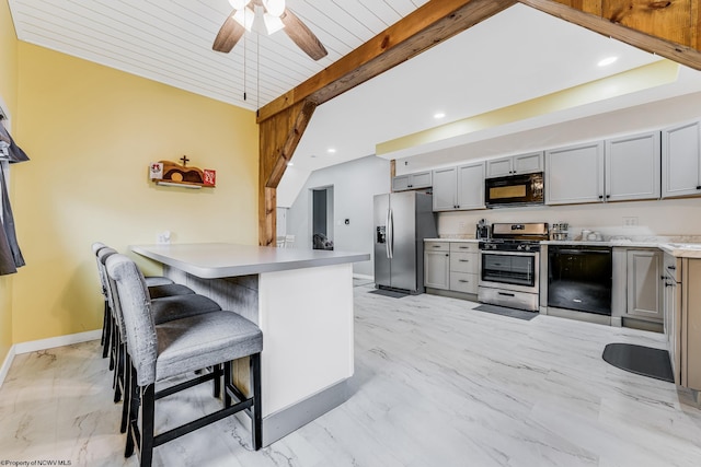 kitchen featuring gray cabinets, beamed ceiling, black appliances, a breakfast bar area, and kitchen peninsula