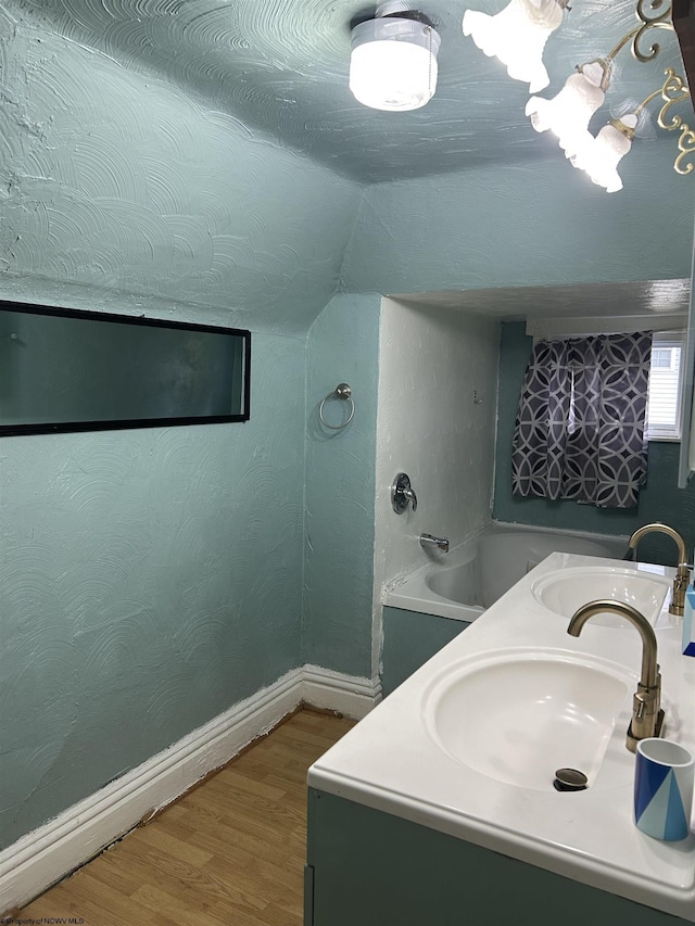 bathroom with vanity, a tub to relax in, wood-type flooring, and vaulted ceiling