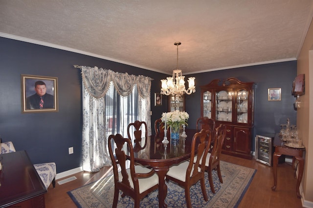 dining space with an inviting chandelier, crown molding, a textured ceiling, dark hardwood / wood-style floors, and beverage cooler