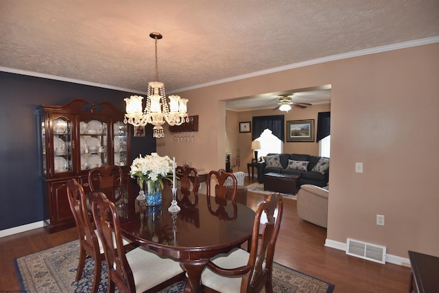 dining area featuring ornamental molding, dark hardwood / wood-style flooring, ceiling fan with notable chandelier, and a textured ceiling