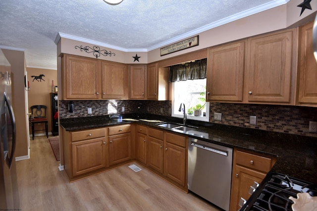 kitchen with appliances with stainless steel finishes, light hardwood / wood-style floors, sink, and dark stone countertops