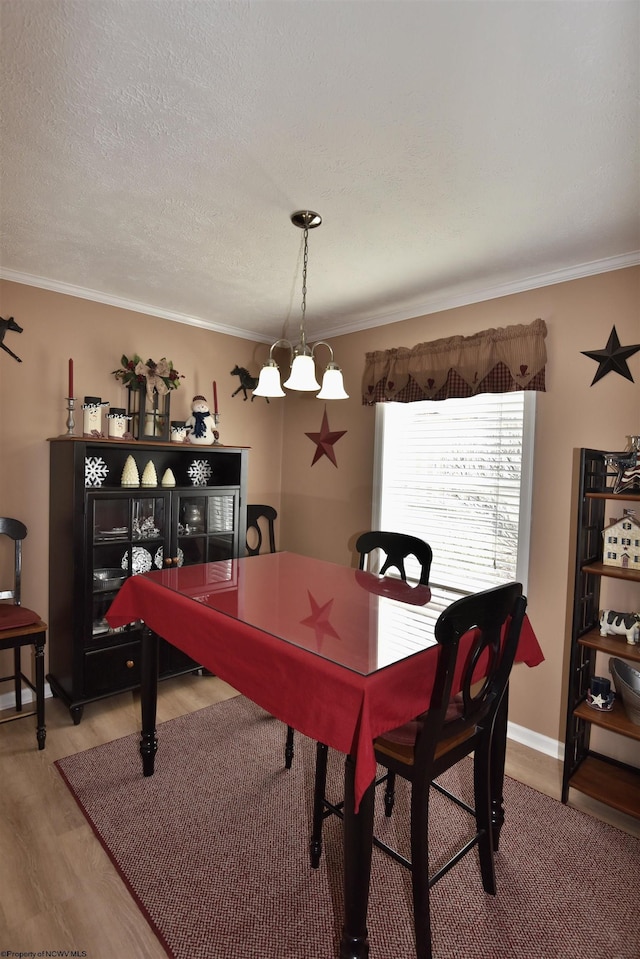 dining space featuring a notable chandelier, hardwood / wood-style flooring, ornamental molding, and a textured ceiling