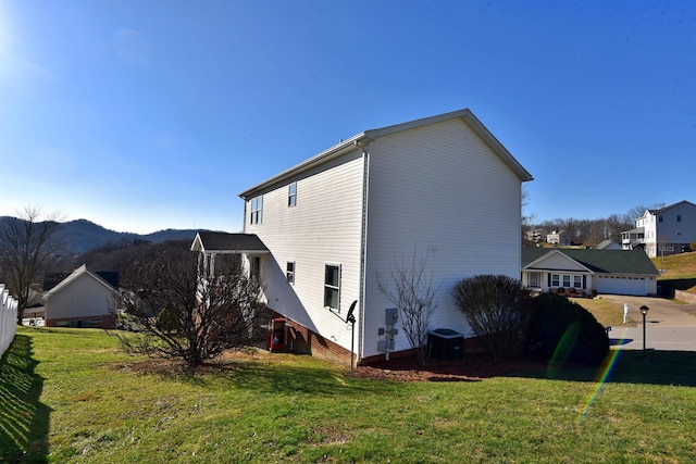 view of property exterior with a garage, a mountain view, a yard, and central AC