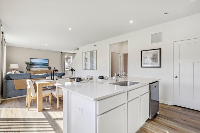 kitchen with sink, a center island with sink, dishwasher, light hardwood / wood-style floors, and white cabinets