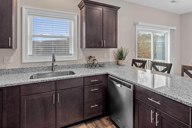 kitchen featuring light stone counters, dishwasher, and sink