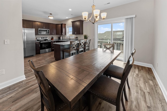 dining area with sink, hardwood / wood-style floors, and a notable chandelier