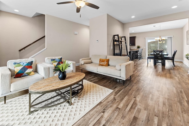 living room featuring ceiling fan with notable chandelier and hardwood / wood-style floors