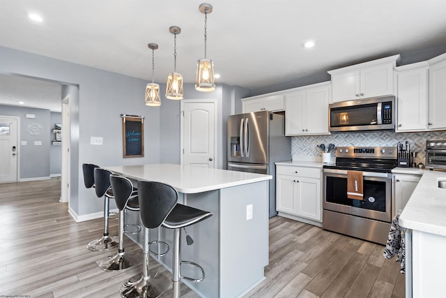 kitchen with a kitchen island, decorative light fixtures, white cabinets, decorative backsplash, and stainless steel appliances