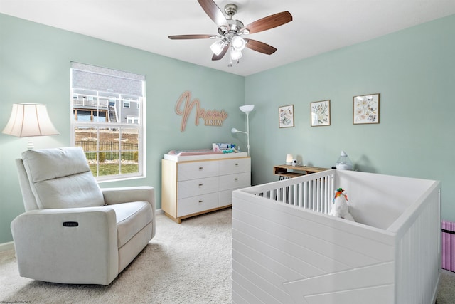 carpeted bedroom featuring a crib and ceiling fan