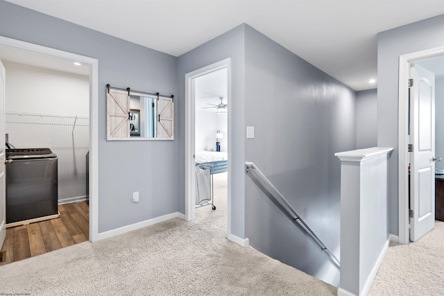 hall with a barn door, light colored carpet, and washer / clothes dryer