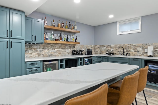 bar with sink, light hardwood / wood-style flooring, backsplash, wine cooler, and light stone countertops