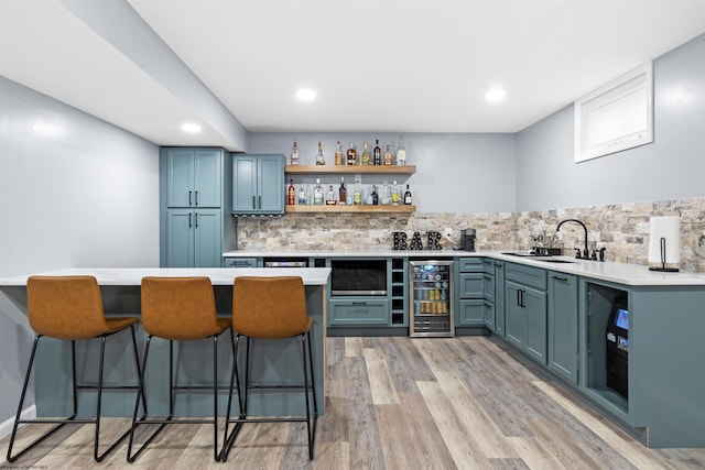 bar featuring wine cooler, backsplash, light hardwood / wood-style floors, and blue cabinetry