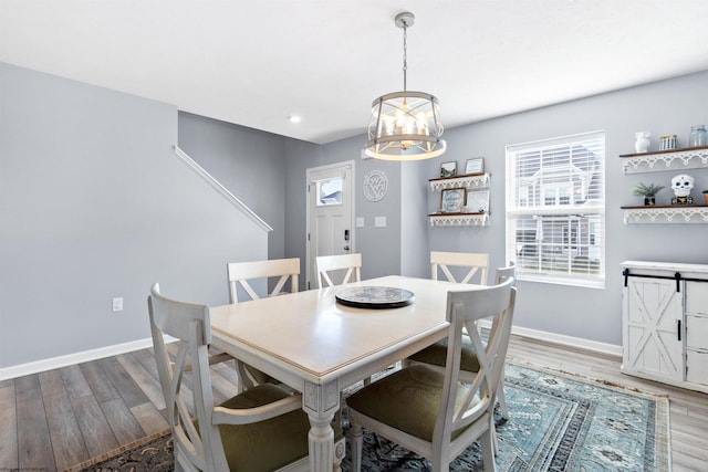 dining area with an inviting chandelier and light hardwood / wood-style flooring