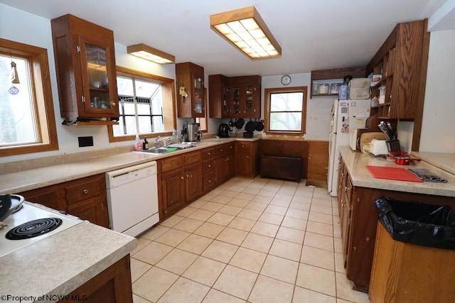 kitchen with light countertops, a wealth of natural light, light tile patterned floors, and white appliances